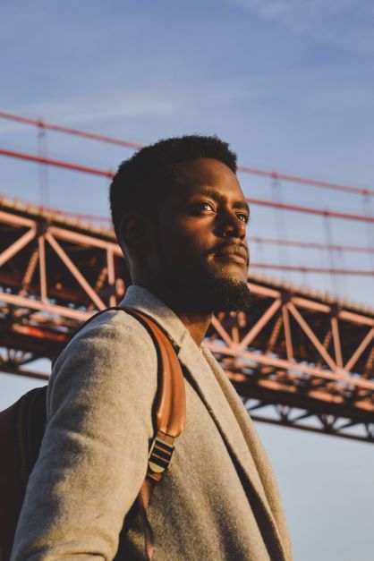 Black  man feeling empowered in tan suit near crane. Its time for support. Lets work on your men's mental health in a safe space. Online therapy in Michigan is a great option. When you're ready, begin therapy for men in Detroit, MI. 