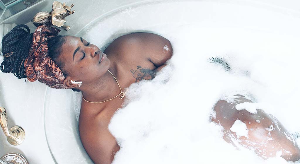 Black woman taking a bath. Find helpful self-care ideas for women and self-care ideas for students at Introspective counseling. Our online therapists in Michigan cannot wait to help you find some helpful self-care tips in Detroit, MI. Call now!