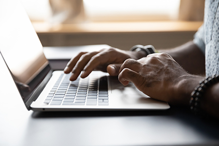 Close up African American male hands typing on laptop keyboard. If you're ready for support, online therapy in Michigan is for you. We can help you with anxiety, trauma, perfectionists, grief, and more. Begin therapy in Detroit, MI when you're ready!