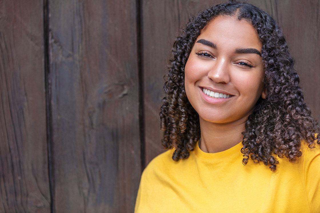 Young black girl in yellow shirt smiling. We serve everyone. If you're seeking therapy for working professionals, therapy for life transitions or therapy for high achievers, we can help! Begin online therapy in Michigan and begin moving forward. 